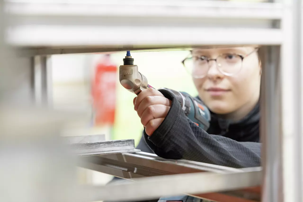 A person using a cordless drill on a metal shelf.