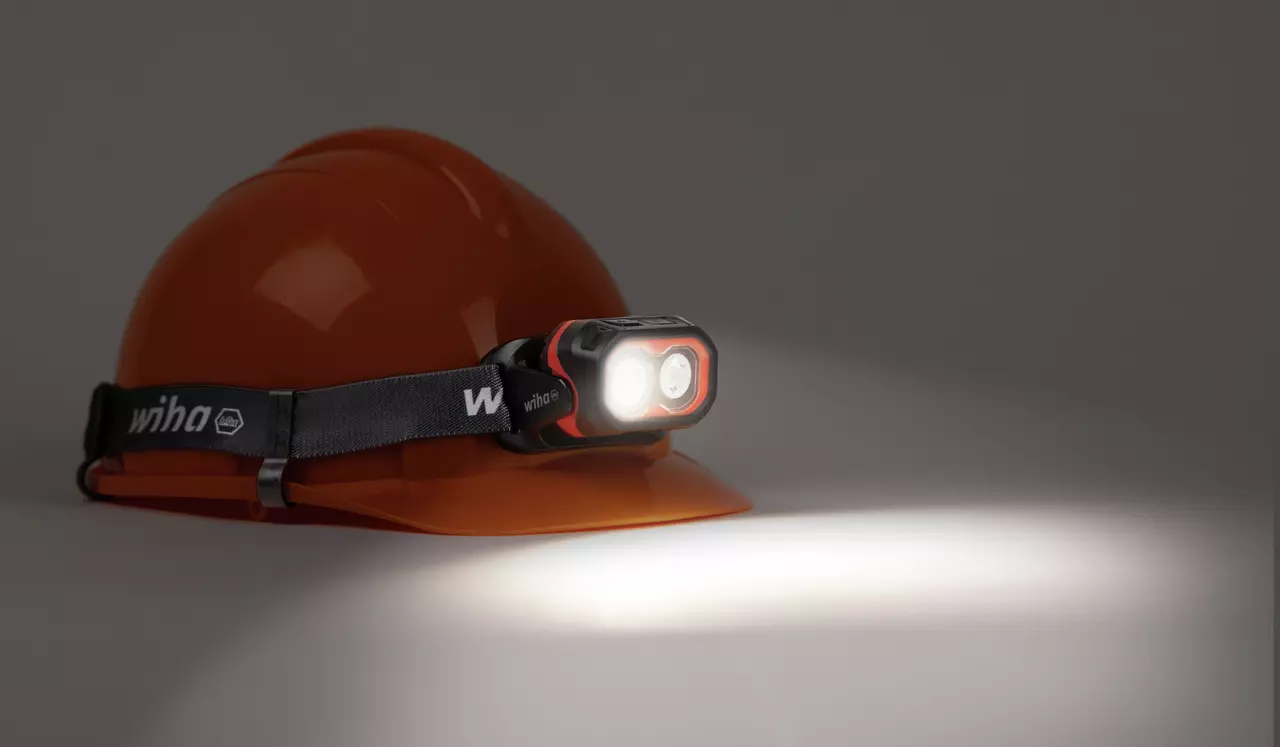 Orange hard hat with a mounted headlamp shining light