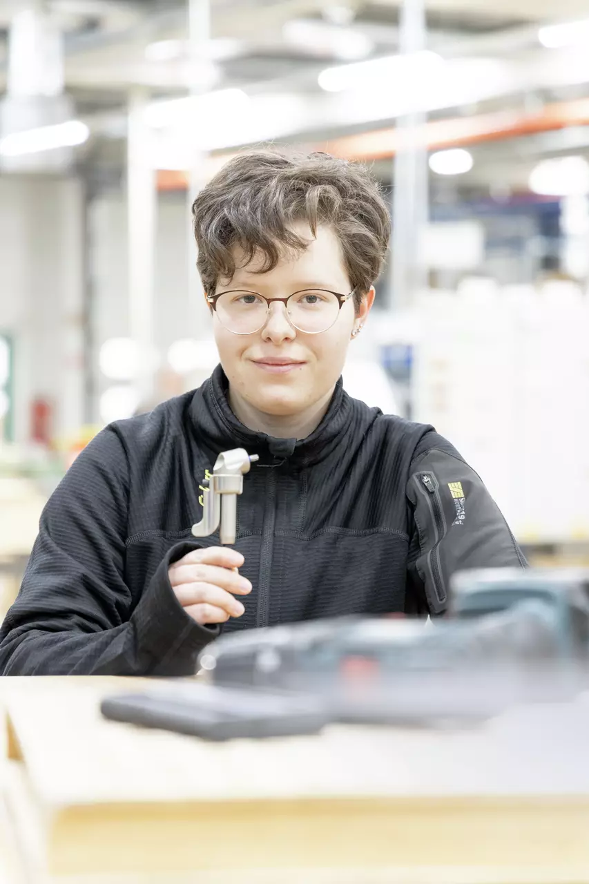 Person holding a metallic tool in a workshop.