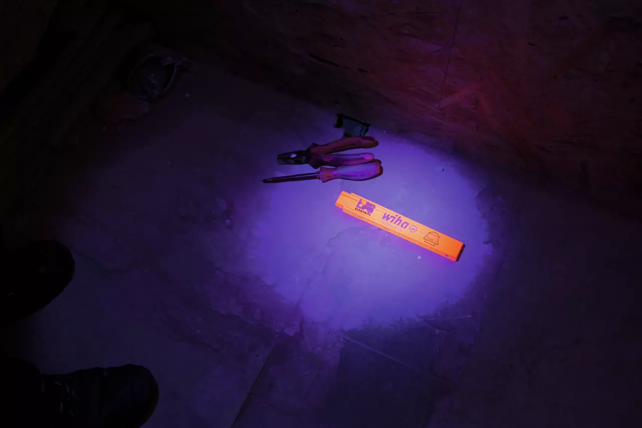 An orange folding ruler and tools on a dimly lit floor.