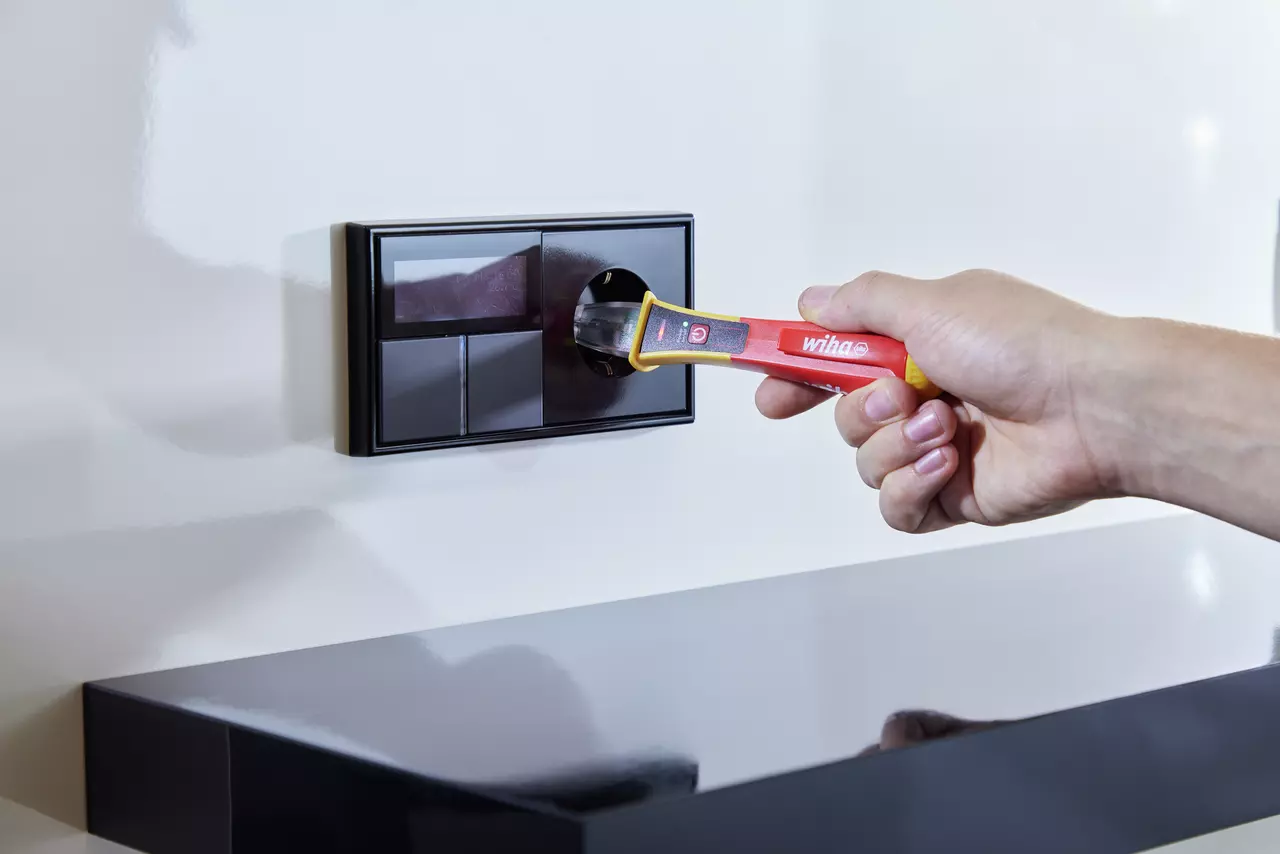 Hand using voltage detector on wall socket