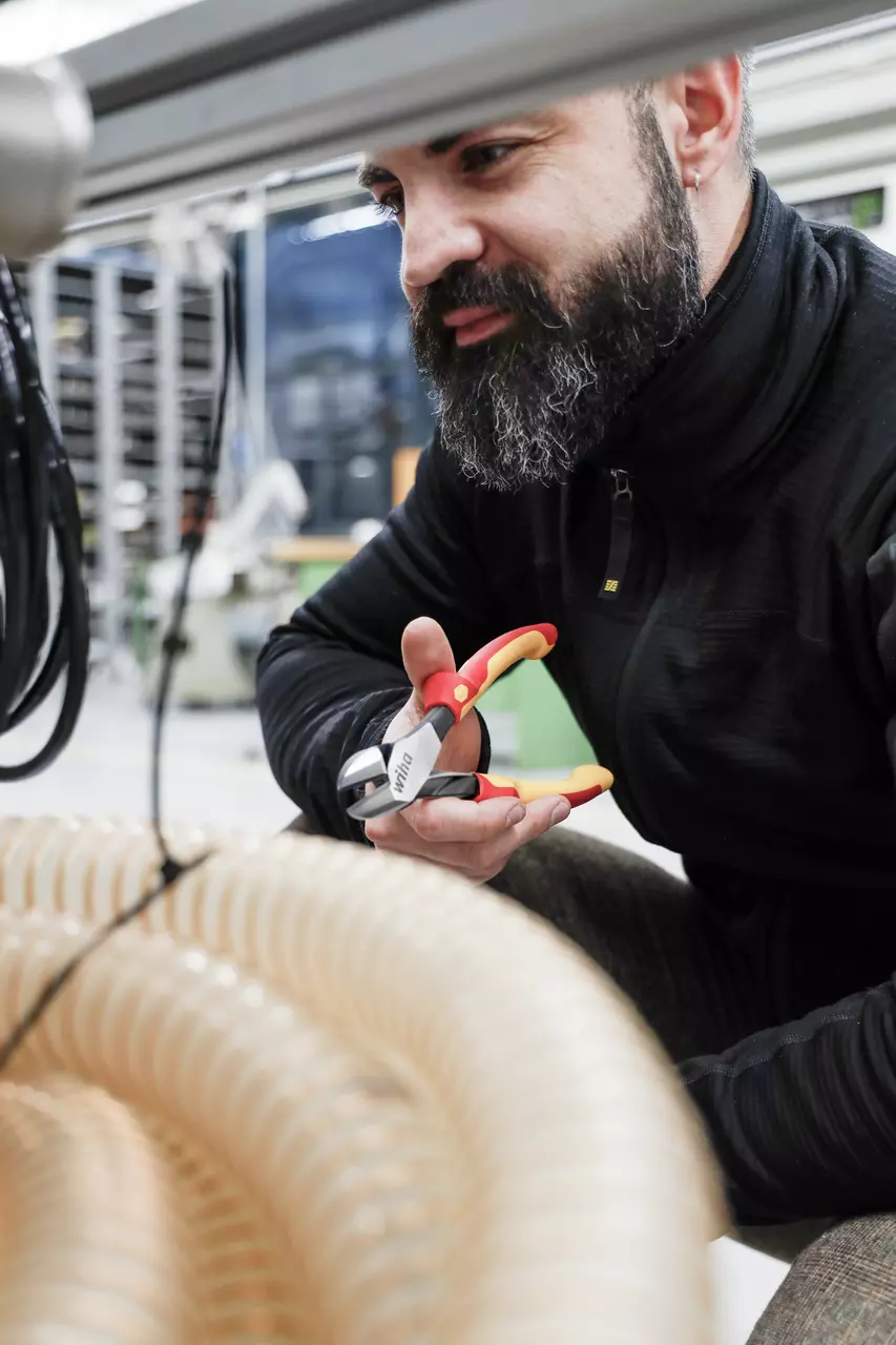 A person using red and yellow side cutters near flexible tubing.