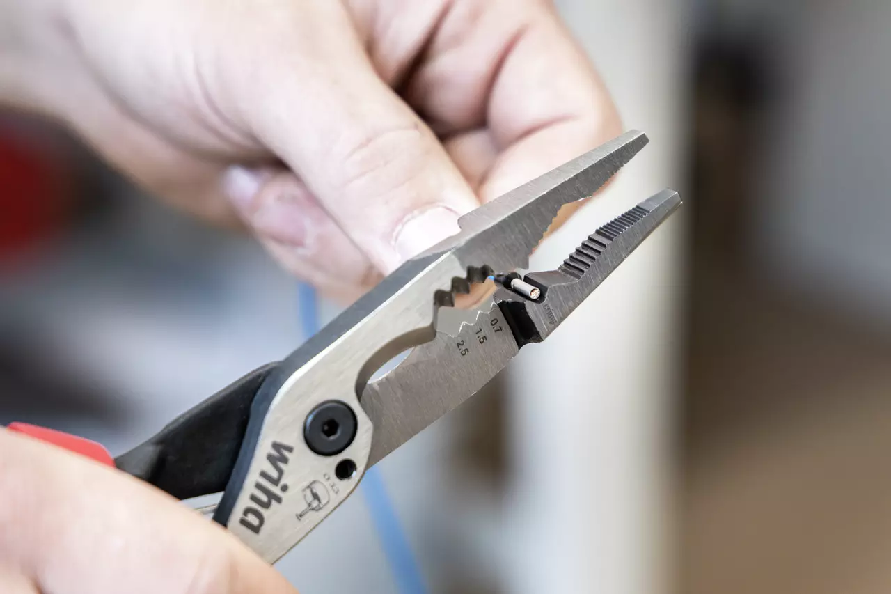 Persoon houdt een tang vast en werkt aan een kabel