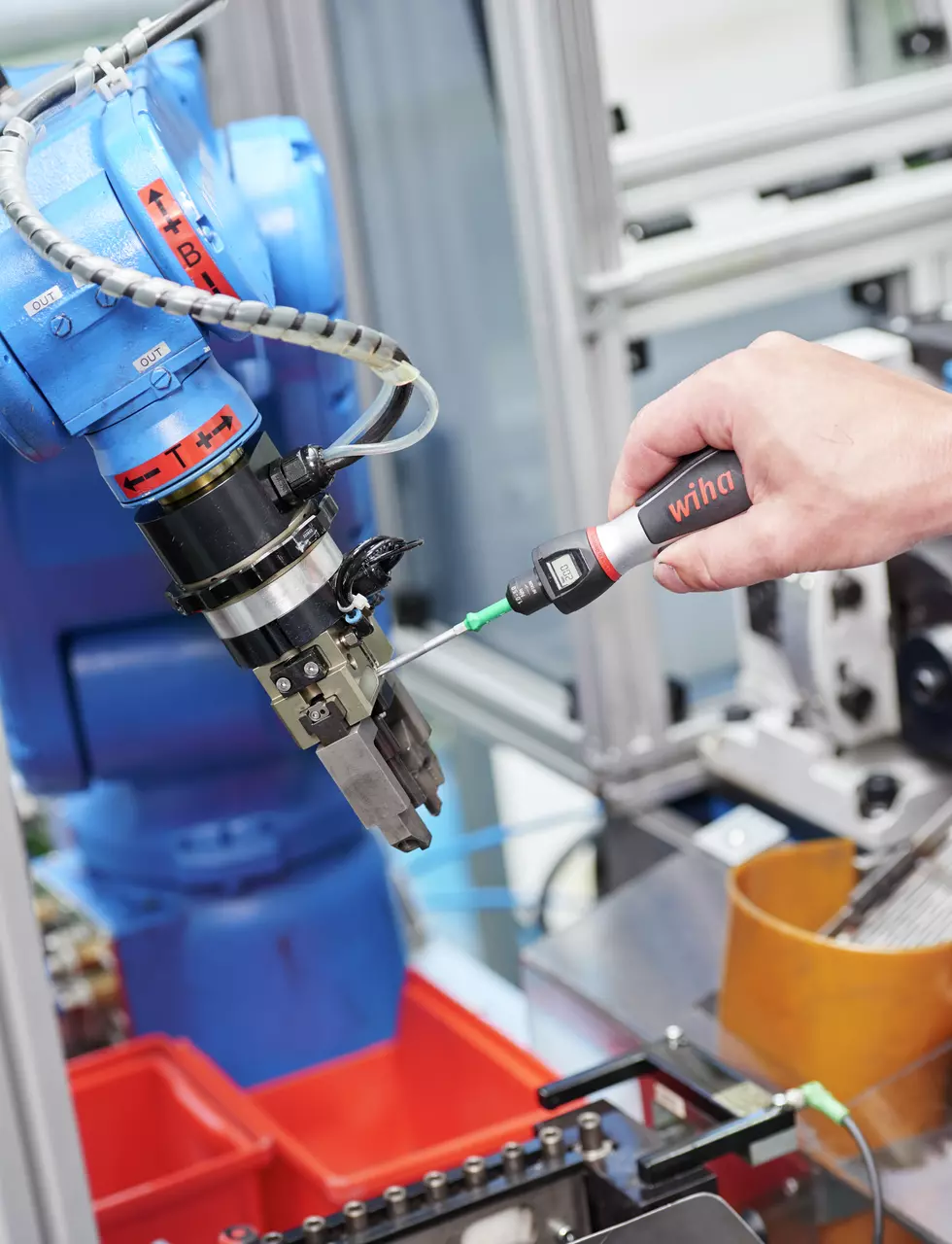 Person using torque screwdriver on robotic arm in industrial setting