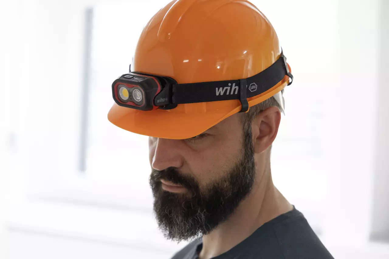 Man wearing an orange hard hat with a headlamp attached