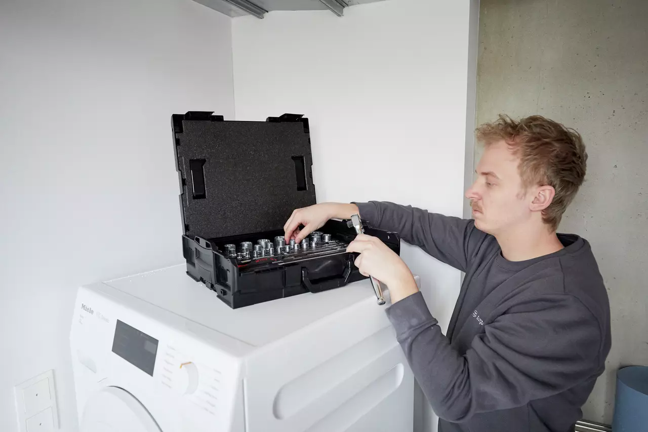 A person using a socket set on top of a washing machine.