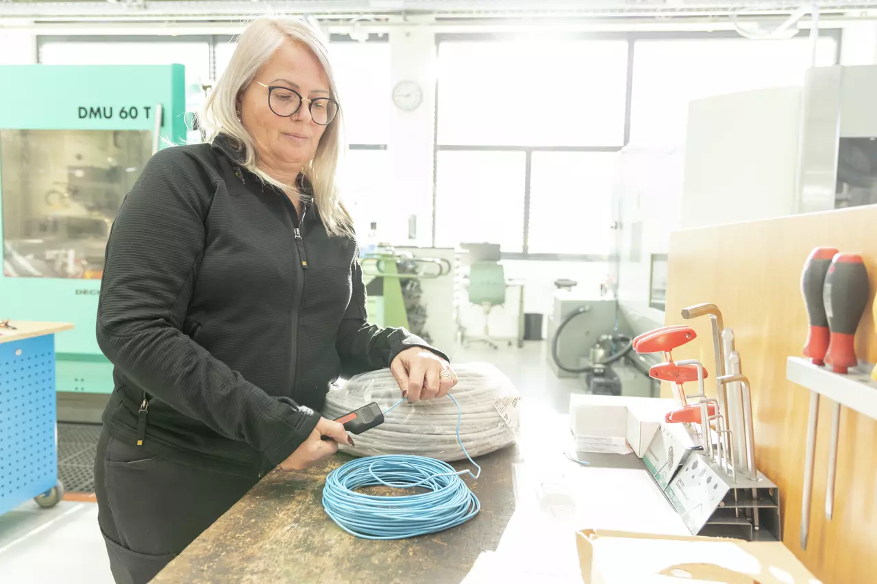 Žena používá nástroj k odizolování drátů v dílně.