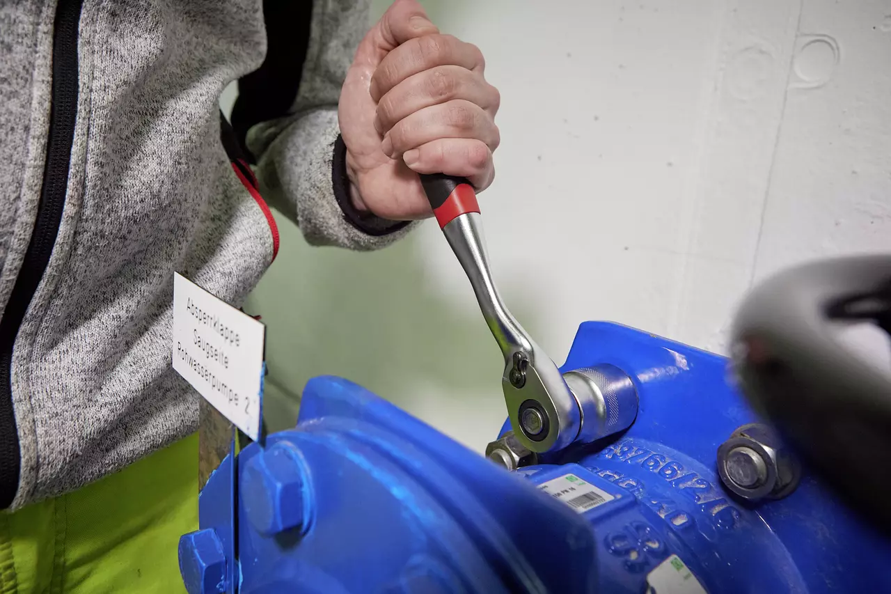 Person using a ratchet wrench on a blue machine part.