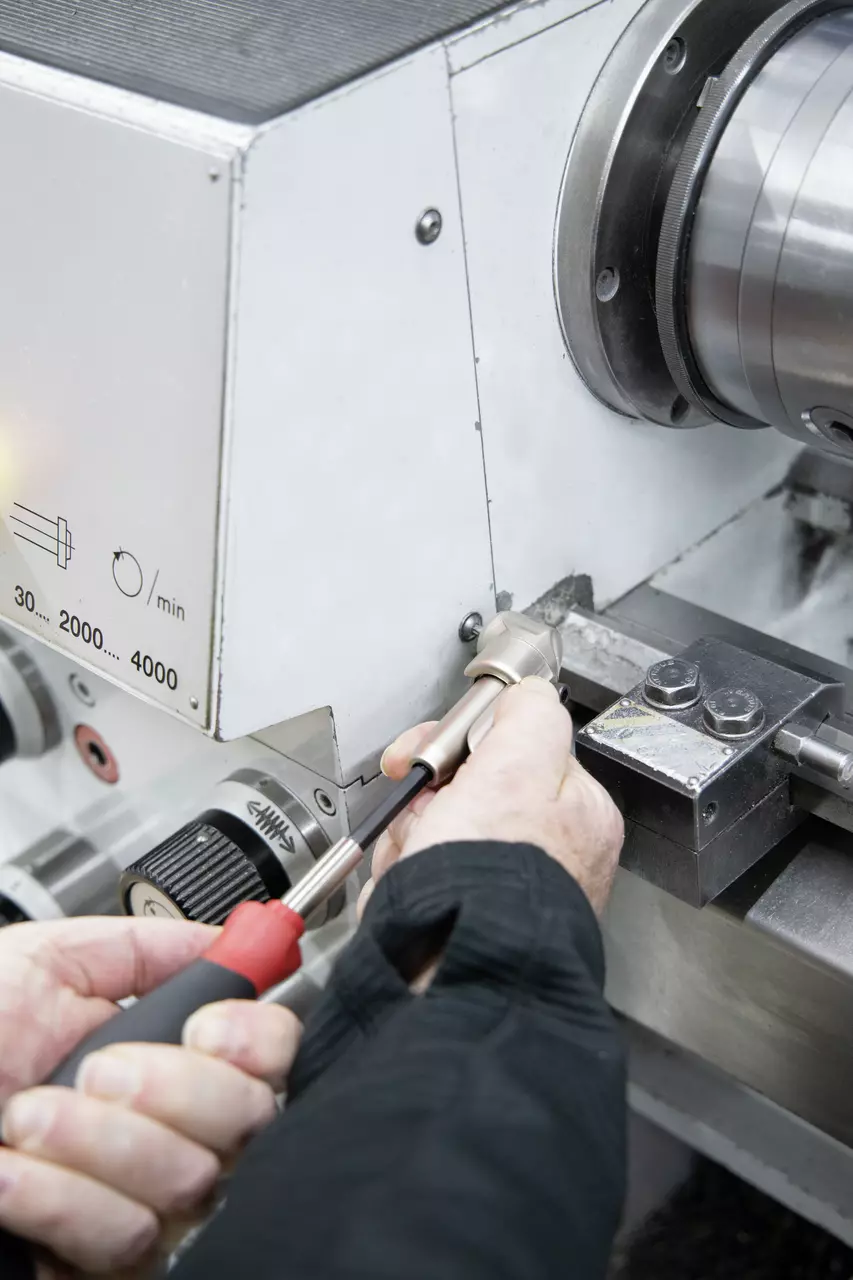 Person using a screwdriver on a metal machine part