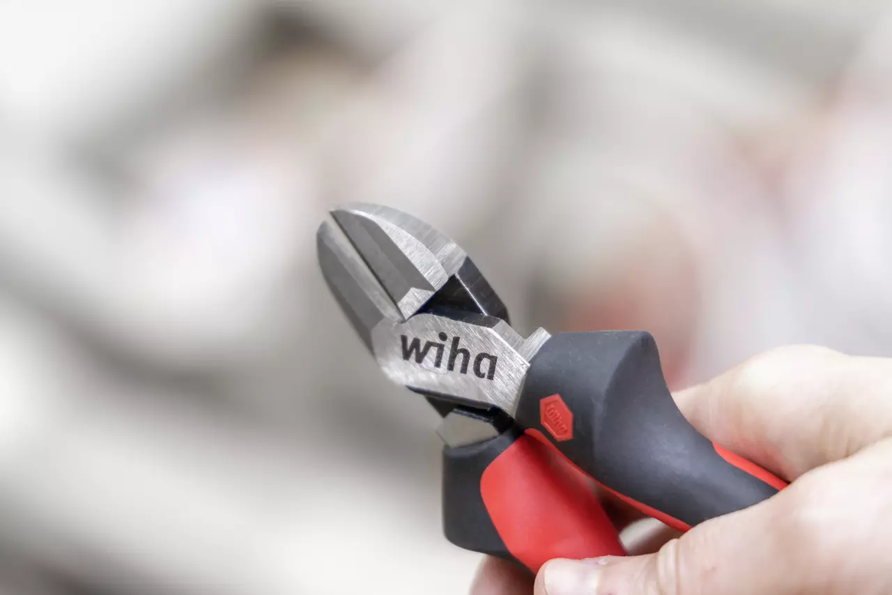 Wire cutter with red and black handles held in a hand.