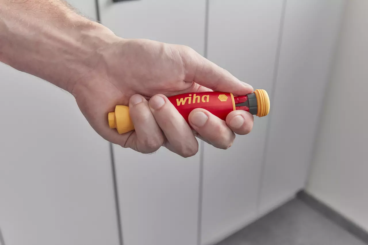Hand holding a red and yellow electric screwdriver with a rounded grip