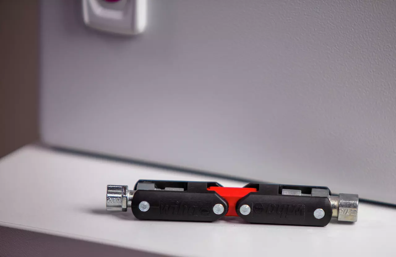 Universal black and red key tool with multiple fittings on a white surface.