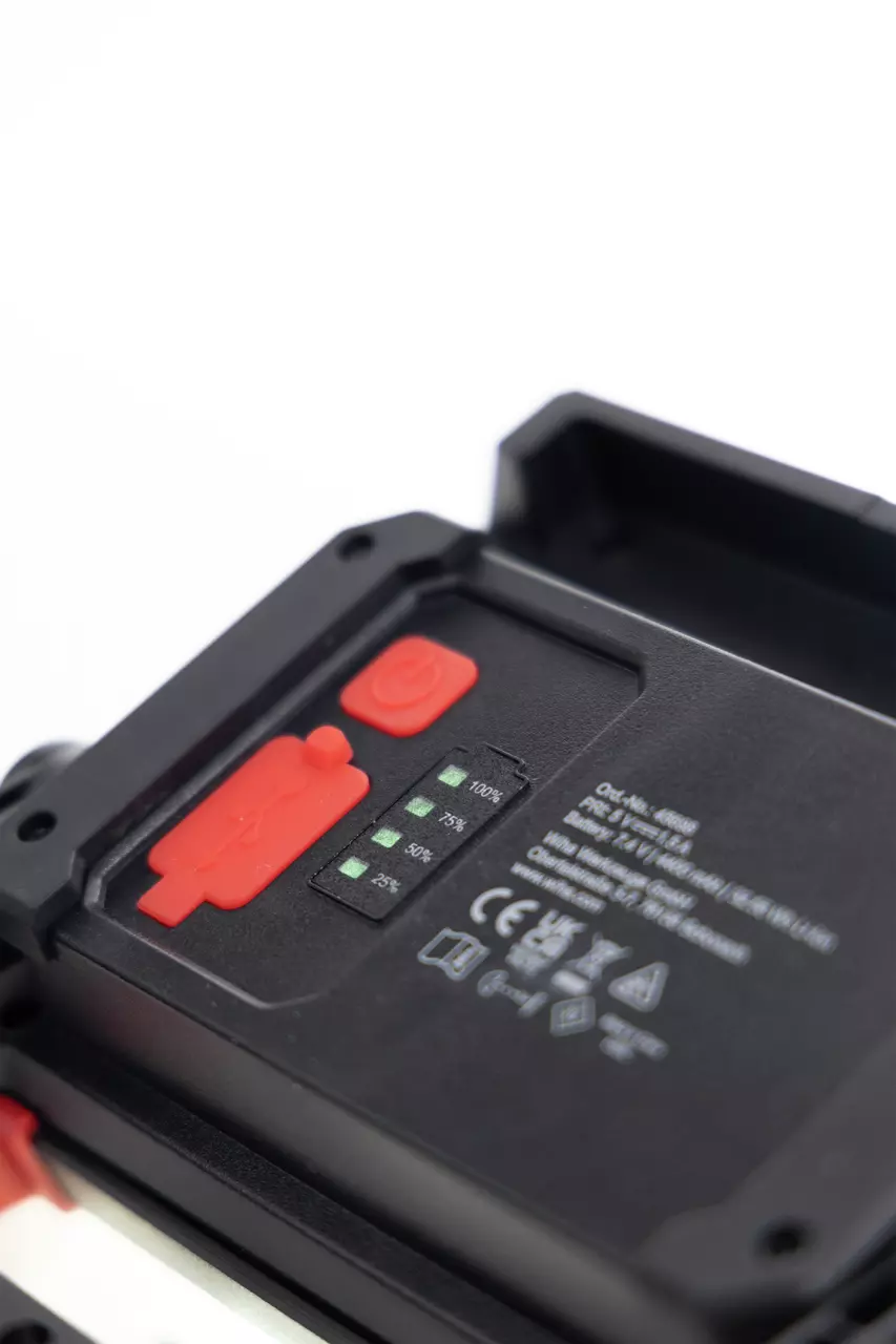 Close-up of a black device with red buttons and battery indicators showing charge levels.