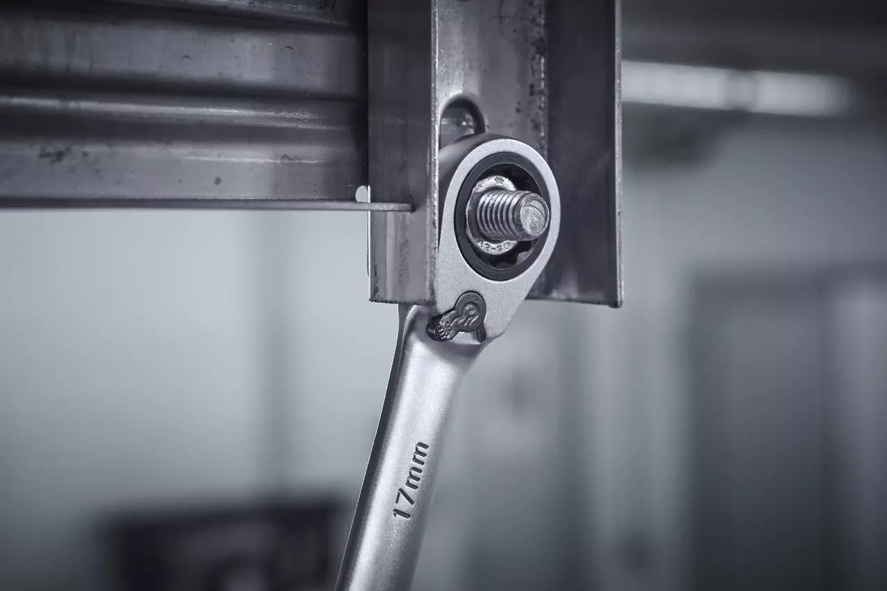 Ratcheting wrench tightening a bolt on a metal frame.