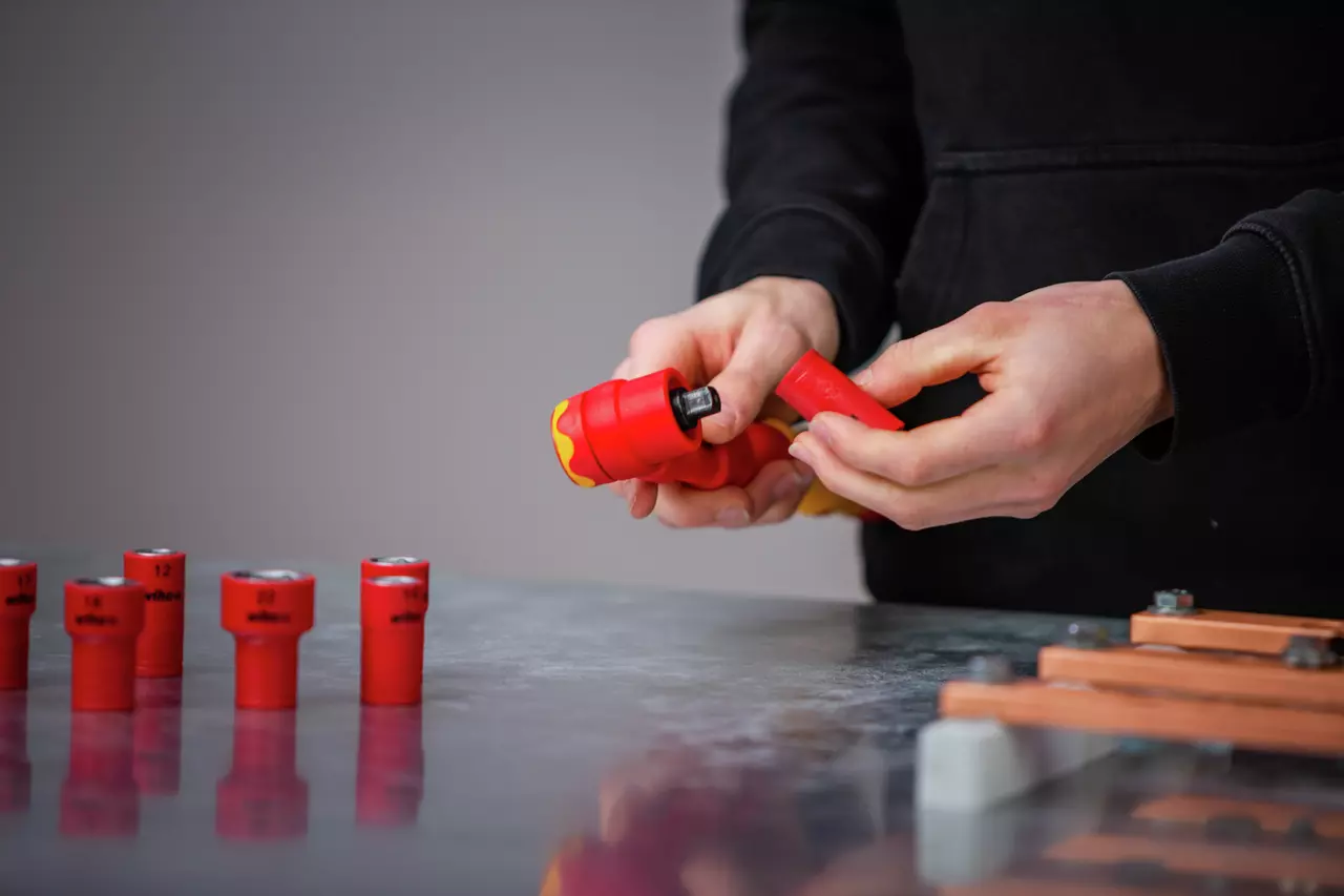 Person using a red torque wrench and sockets on a table.