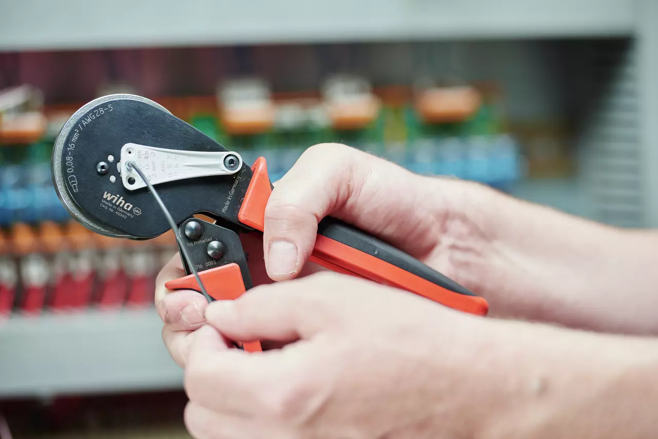 Person using an automatic crimping tool to process a wire
