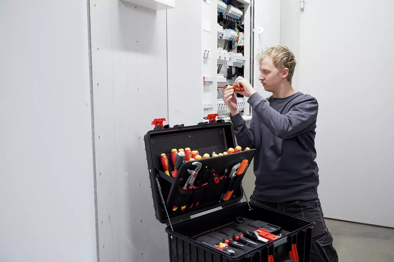 Person working on electrical panel with tool case open