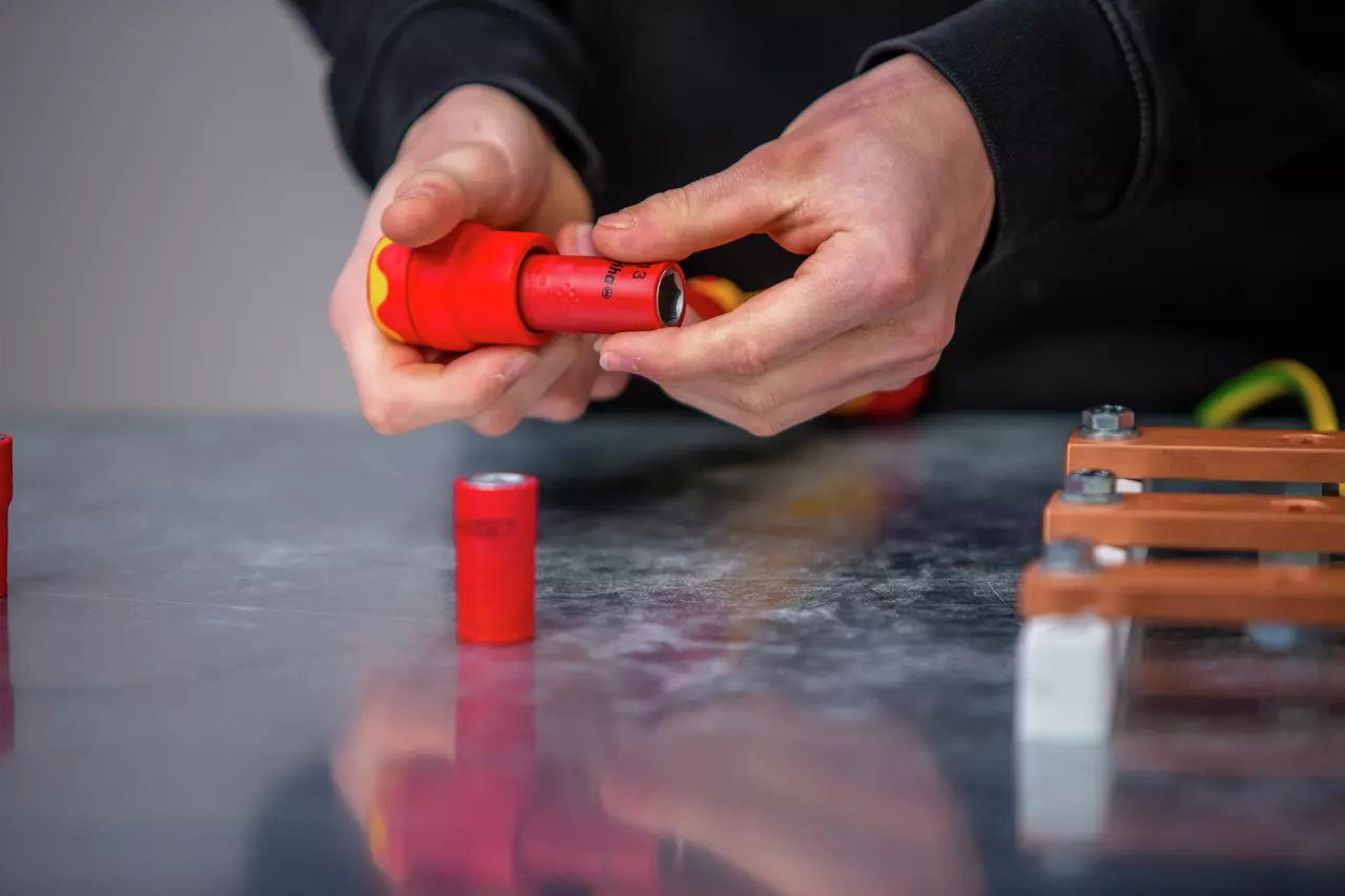 Person using a red torque wrench on a metal surface.