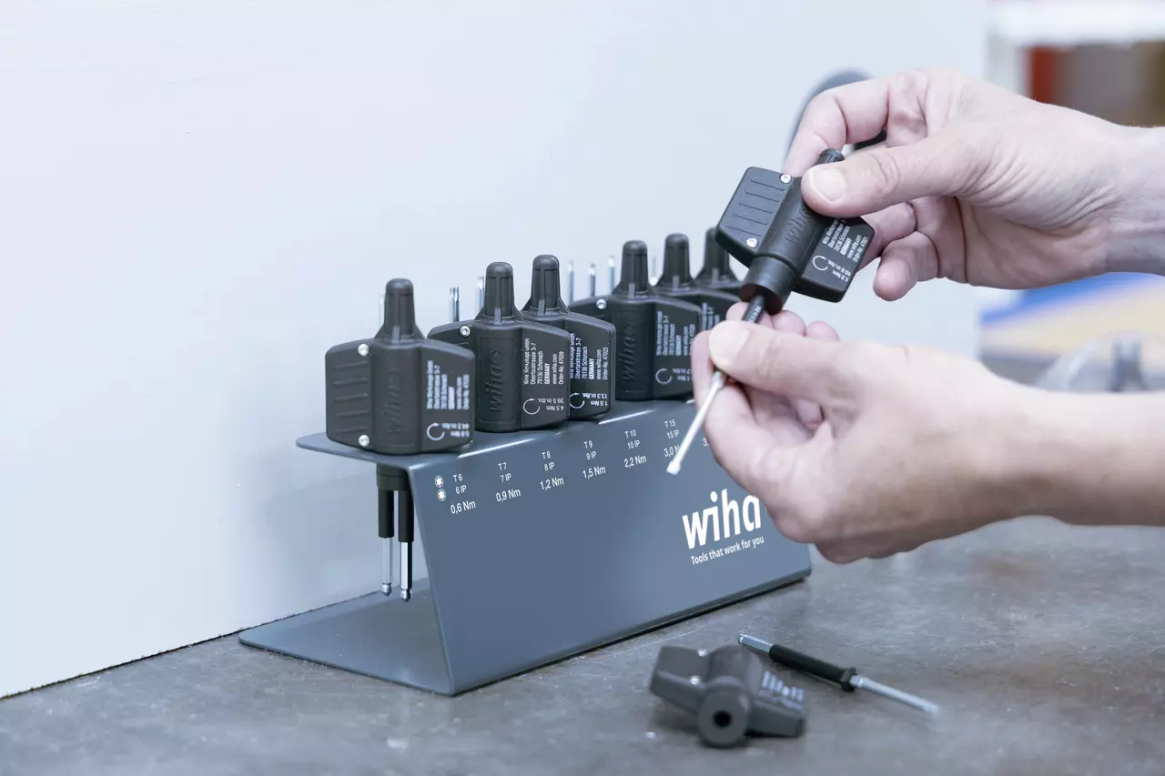 Hands using a torque screwdriver set with black handles on a stand
