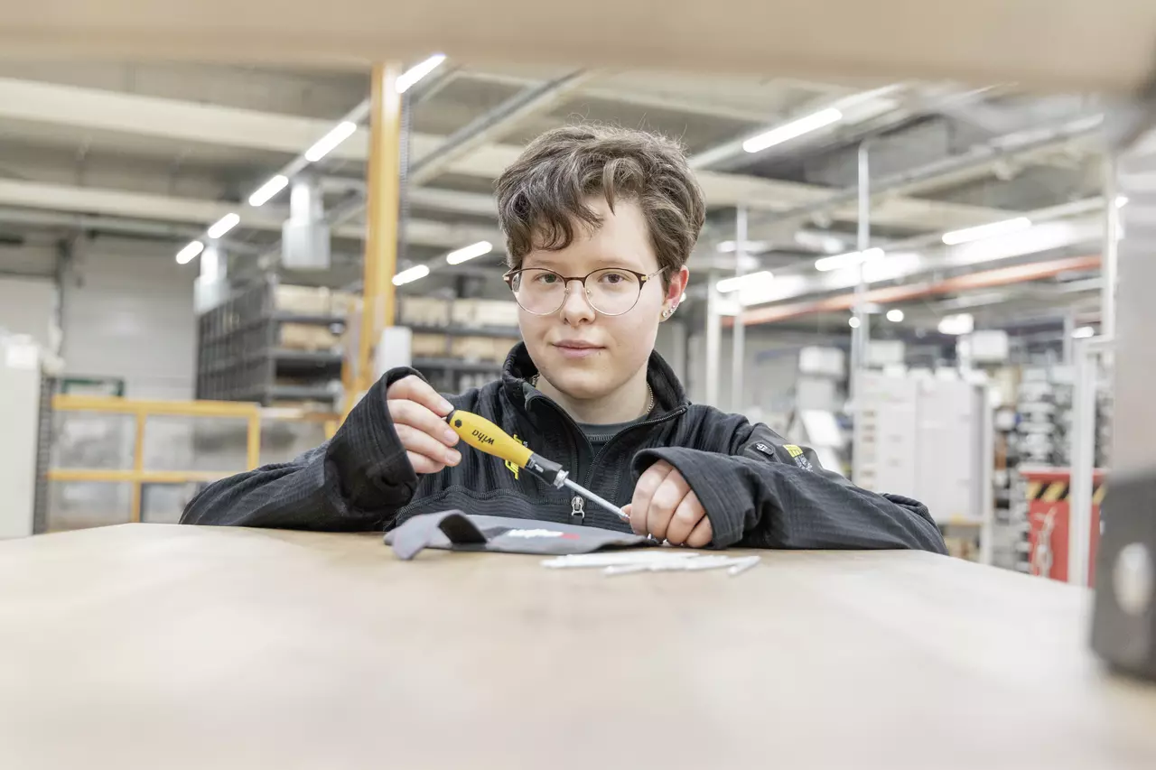 A person in work attire holding a yellow electric screwdriver.
