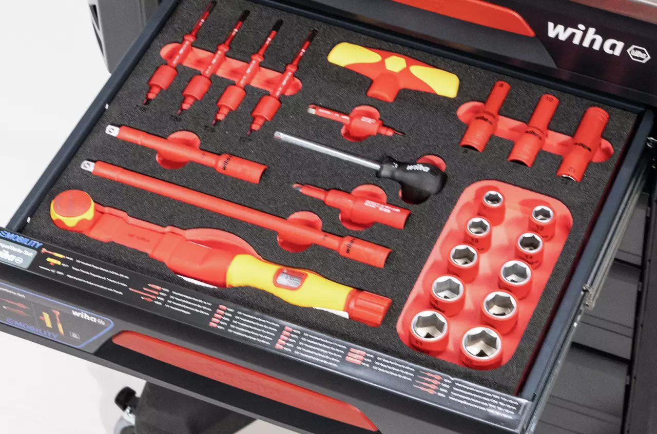 Tool drawer with red and yellow insulated tools and sockets in foam cutouts.