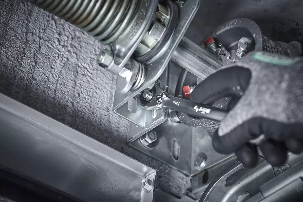 A person uses a ratchet wrench on a metal mechanism
