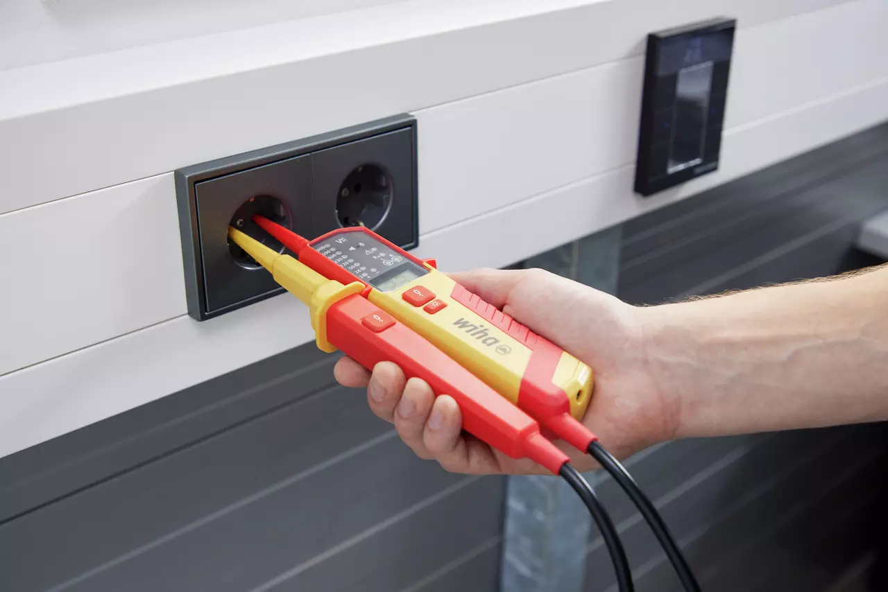Person testing socket with voltage and continuity tester