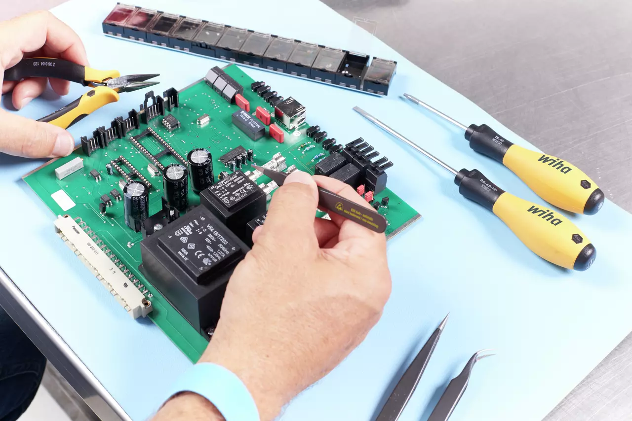 Person working on a circuit board with pliers and tweezers